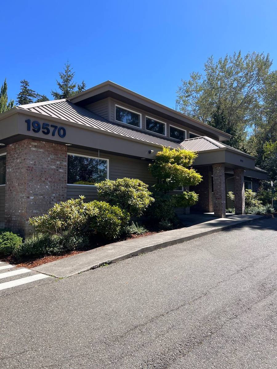 Clifton Hollow Animal Hospital's building seen from the street, with conifers and rhododendrons around it
