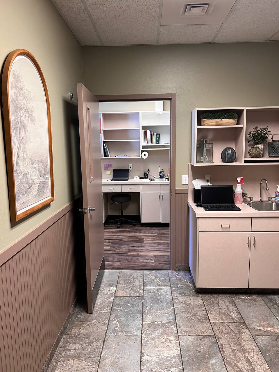 An exam room with its sink, counter, and shelves, opening onto the doctors' office